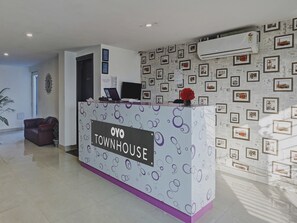 Una recepción con un letrero que dice 'OYO TOWNHOUSE' y una pared decorada con cuadros enmarcados.