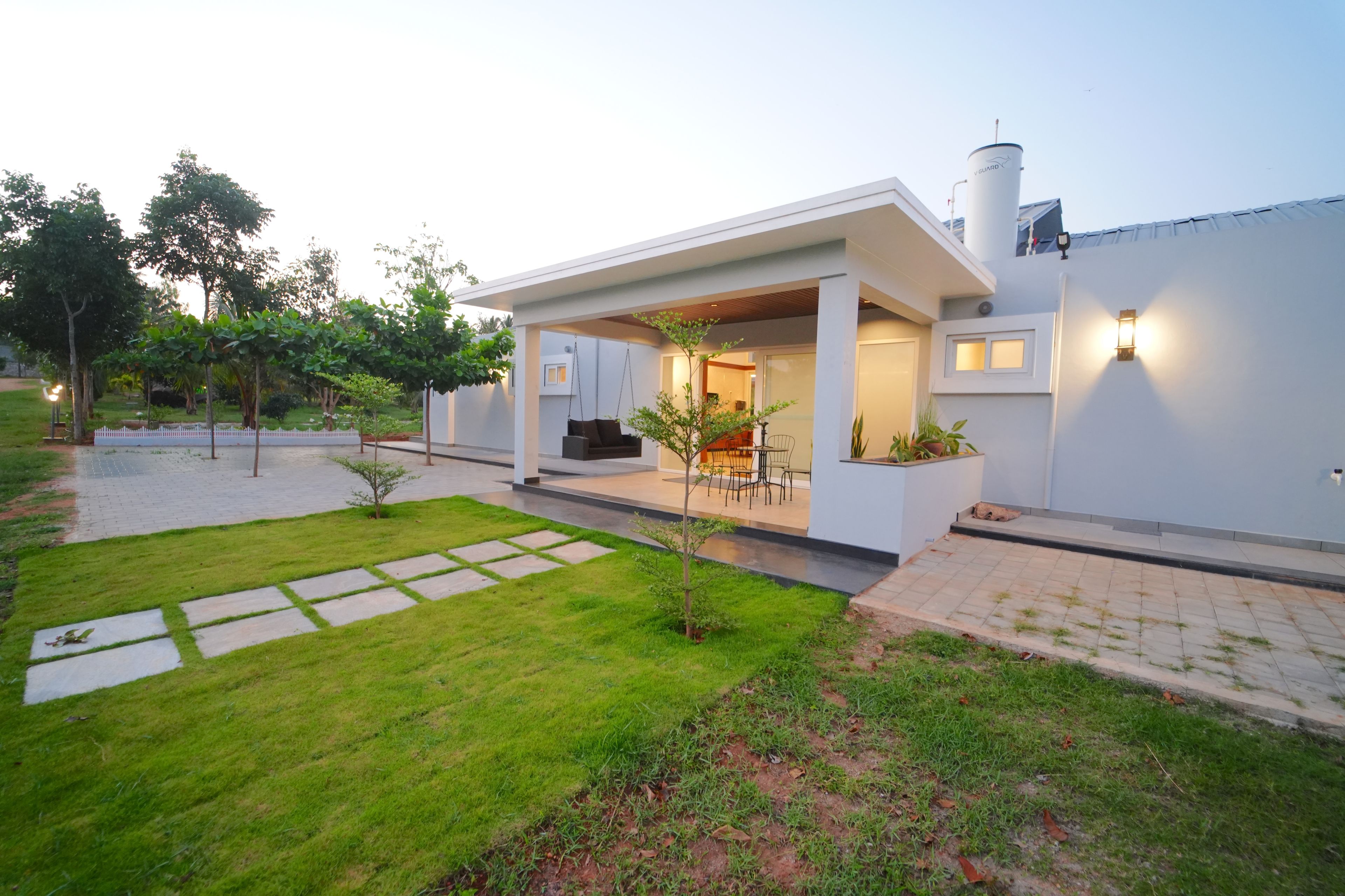 A modern house with a covered patio, a small garden, and a water tank.