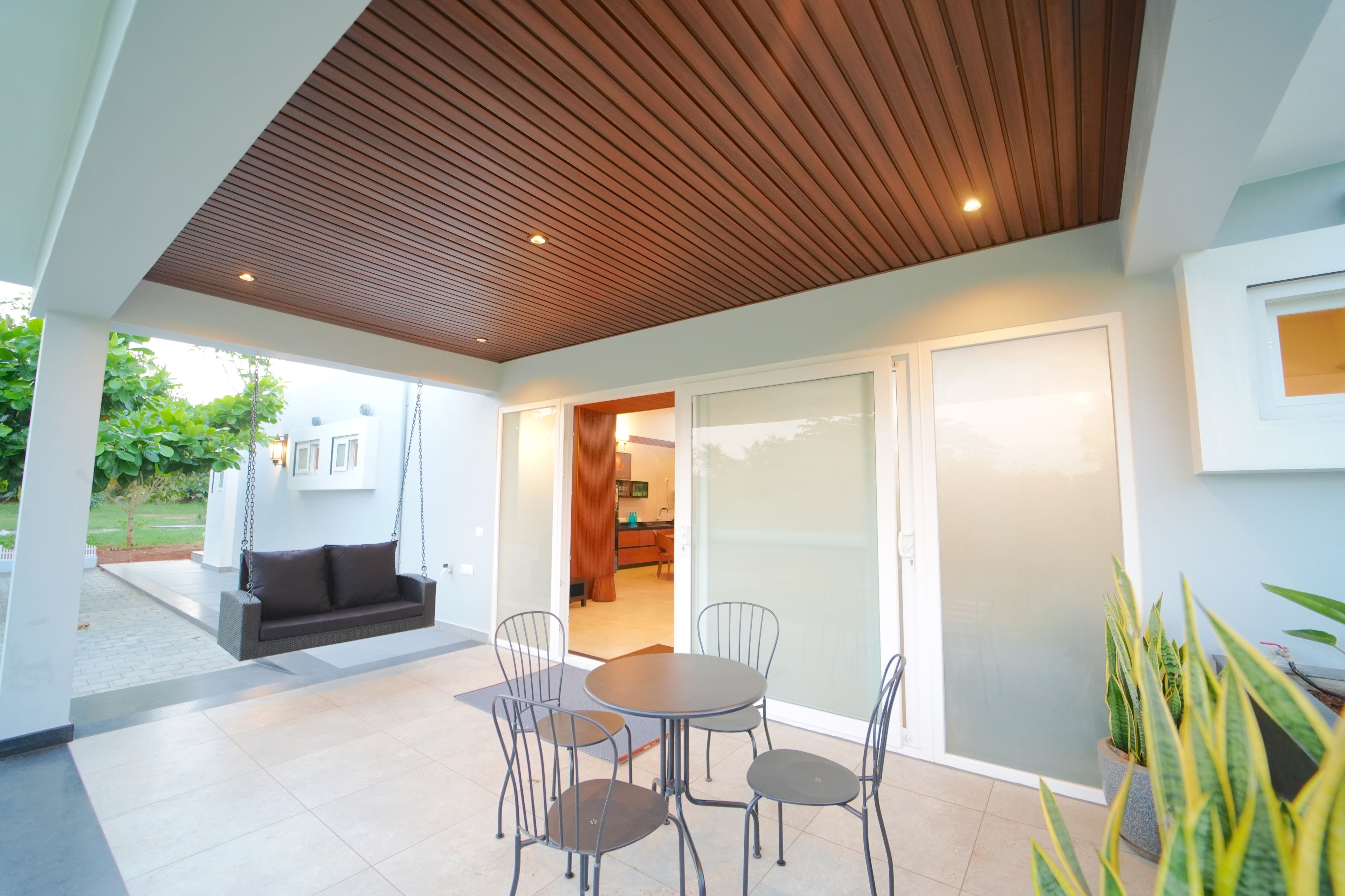 An outdoor patio with a wooden ceiling, a dining table with chairs, and a sofa.