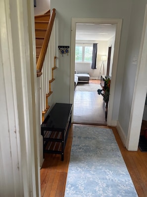 A hallway with a wooden staircase, a bench, and a rug leading to a bedroom with a bed and a window. - Welcome home ! 
West end of Halifax, 3 bedroom home is waiting for you! (Halifax)