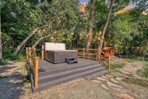 Una terraza de madera con un jacuzzi y una cabaña de madera.