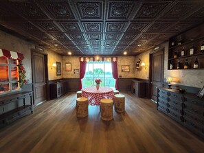 Ein Zimmer mit Holzboden, einem Tisch mit kariertem Tischläufer und einem Weinregal.