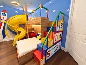 A child's playroom with a bunk bed, a slide, and a wall with alphabet blocks. - Ever After Estate | Luxury 12 Bed Home | 9 mins to Disney World (Kissimmee)