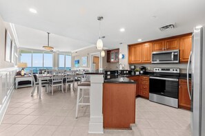 A modern kitchen with wooden cabinets, stainless steel appliances, and a large island. - Elegant Oceanfront Condo, Indoor and Outdoor Pools | Mar Vista Grande - 1511 (North Myrtle Beach)