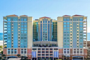A multi-story hotel with a central atrium, balconies, and a view of the ocean. - Elegant Oceanfront Condo, Indoor and Outdoor Pools | Mar Vista Grande - 1511 (North Myrtle Beach)