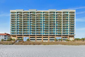 Een hotel met meerdere verdiepingen en balkons, nabij een strand.