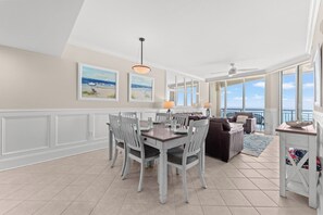 A spacious living area with a dining table, chairs, and a sofa. There is a balcony with a view of the ocean. - Elegant Oceanfront Condo, Indoor and Outdoor Pools | Mar Vista Grande - 1511 (North Myrtle Beach)