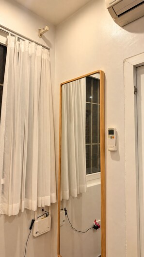A bathroom with a mirror, a window with curtains, an air conditioning unit, and a wall-mounted device. - Cozy 2BR Private Home in Central Hanoi Old Quarter - Kichen, Washer, Wifi & AC (Hoan Kiem)
