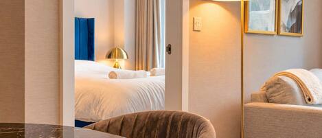 A hotel room with a bed, a sitting area with a sofa, a round table, and a lamp.