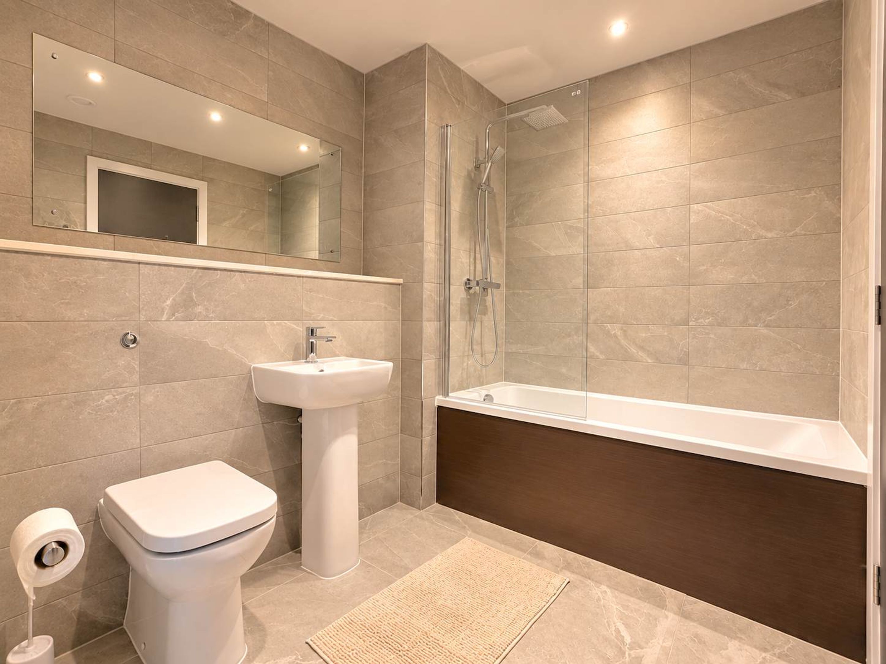 A modern bathroom with a toilet, sink, shower, and bathtub.