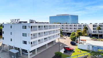 A multi-story hotel with a prominent 'Sailport' sign, a parking area, and a modern building in the background.