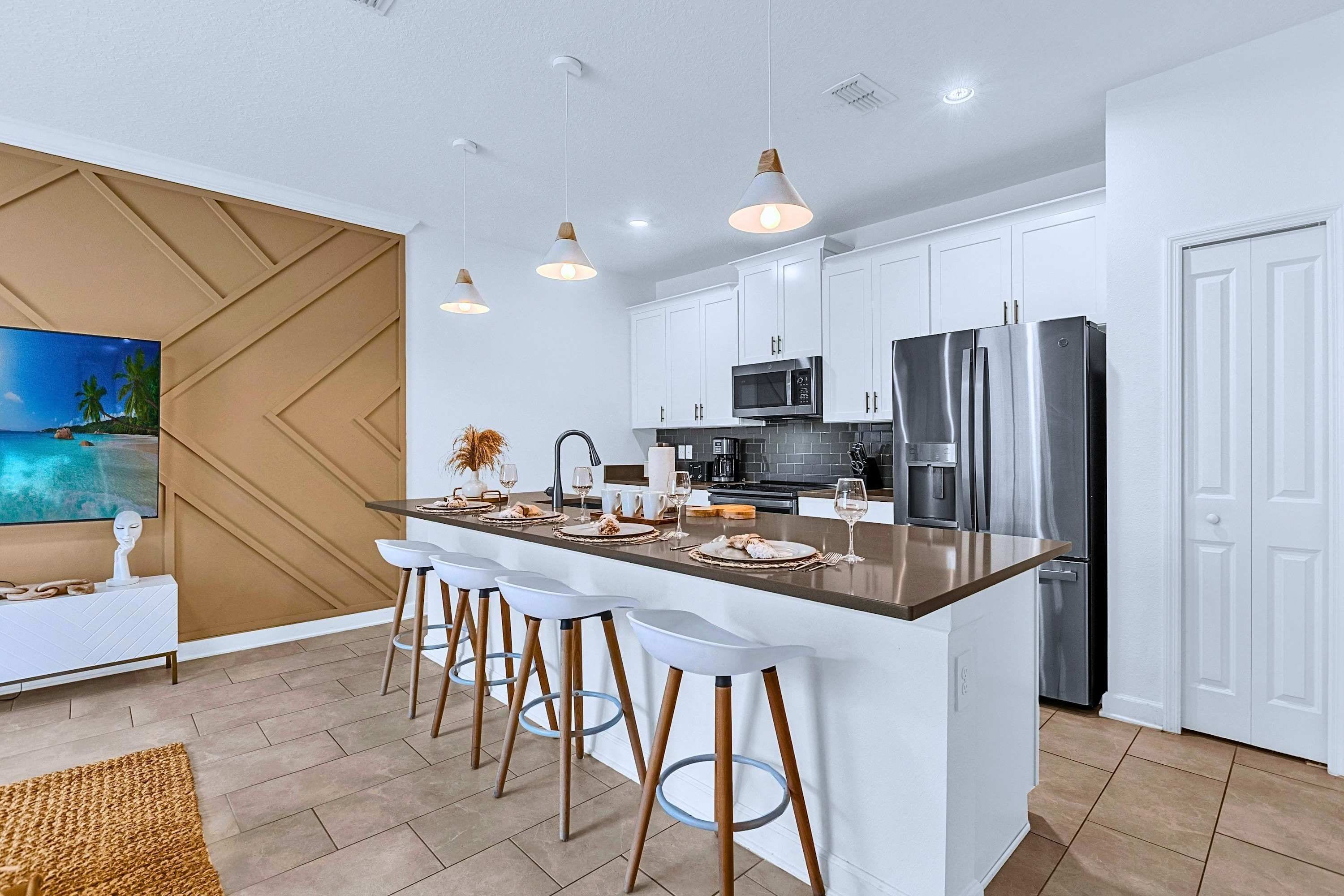 A modern kitchen with white cabinets, stainless steel appliances, and a central island with bar stools.