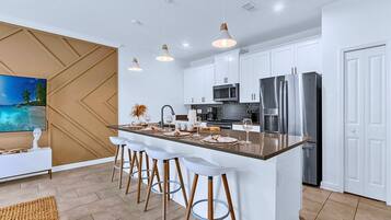 A modern kitchen with white cabinets, stainless steel appliances, and a central island with bar stools.
