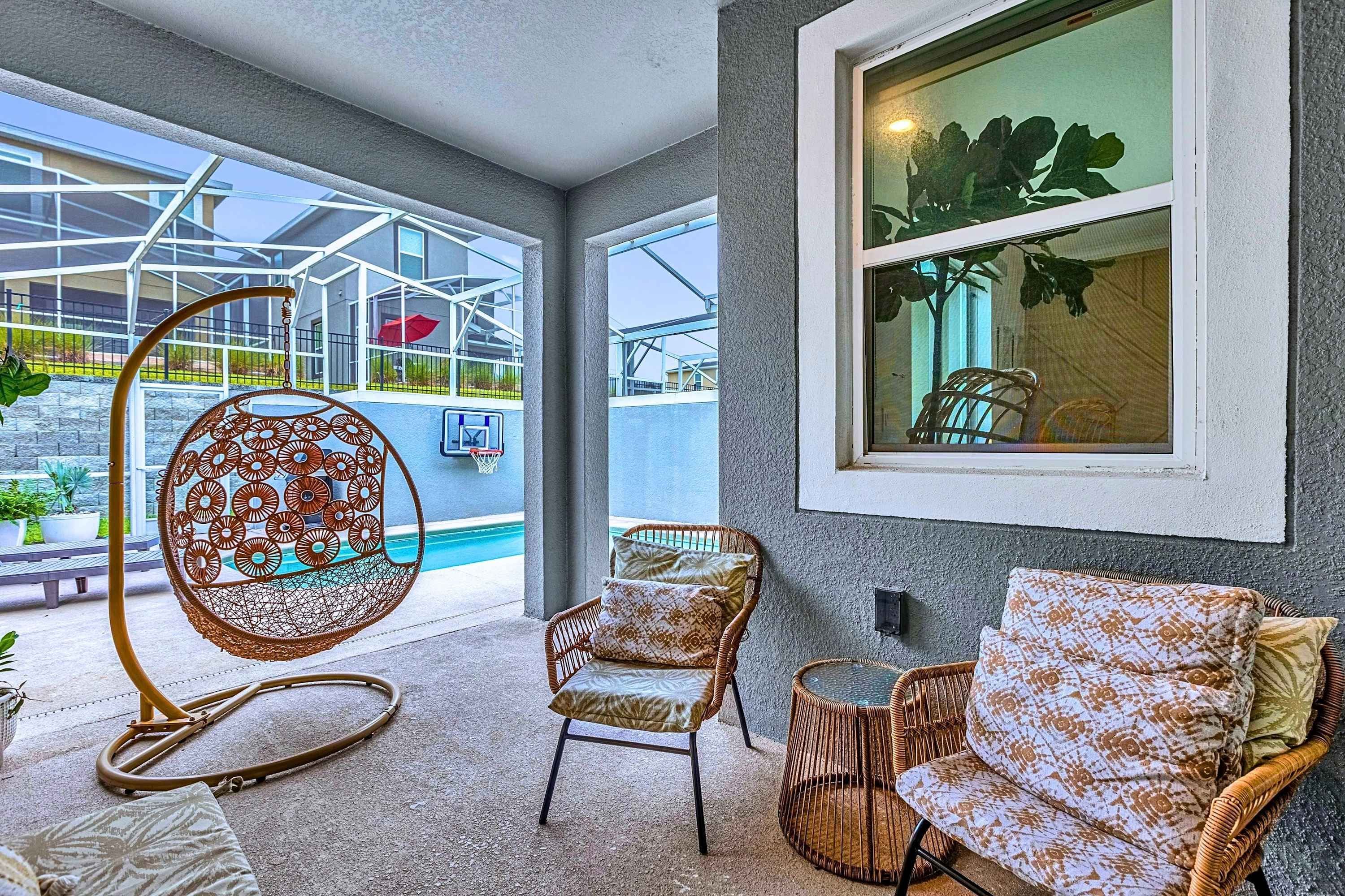 A room with a pool, wicker furniture, and a view of a building.