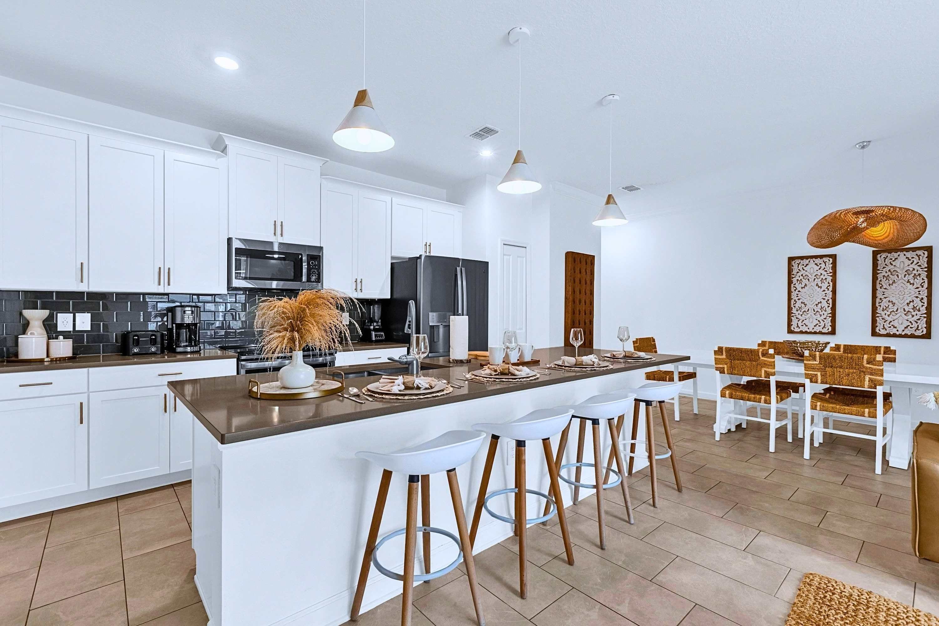 Una cocina moderna con armarios blancos, electrodomésticos de acero inoxidable y una isla central con taburetes.