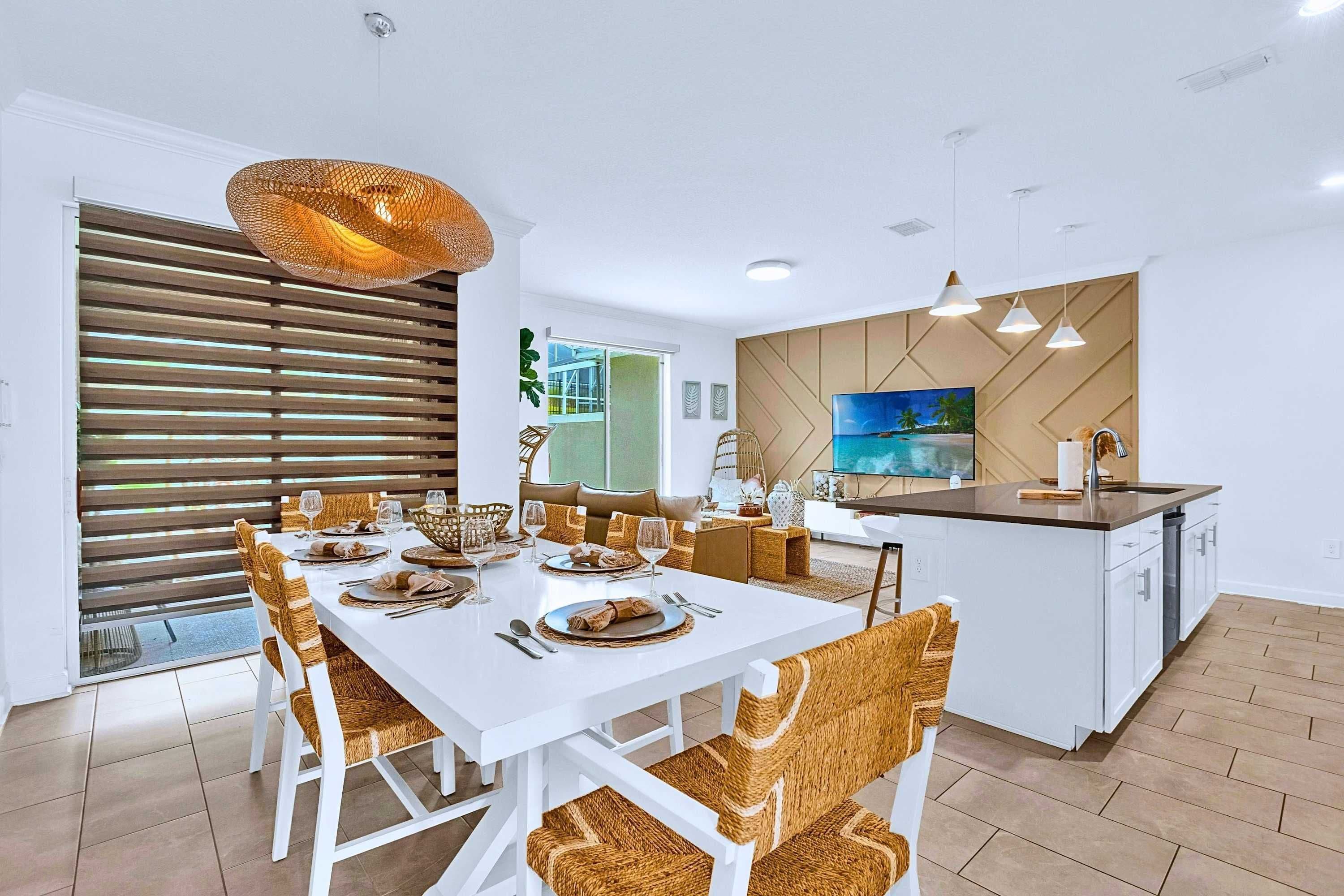 Un comedor moderno con una mesa blanca dispuesta para seis personas, rodeada de sillas de mimbre.