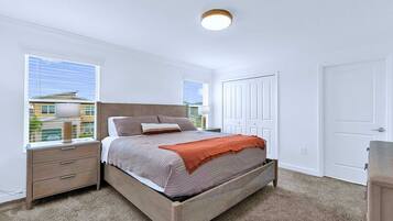 A bedroom with a bed, nightstands, a window, and a door.