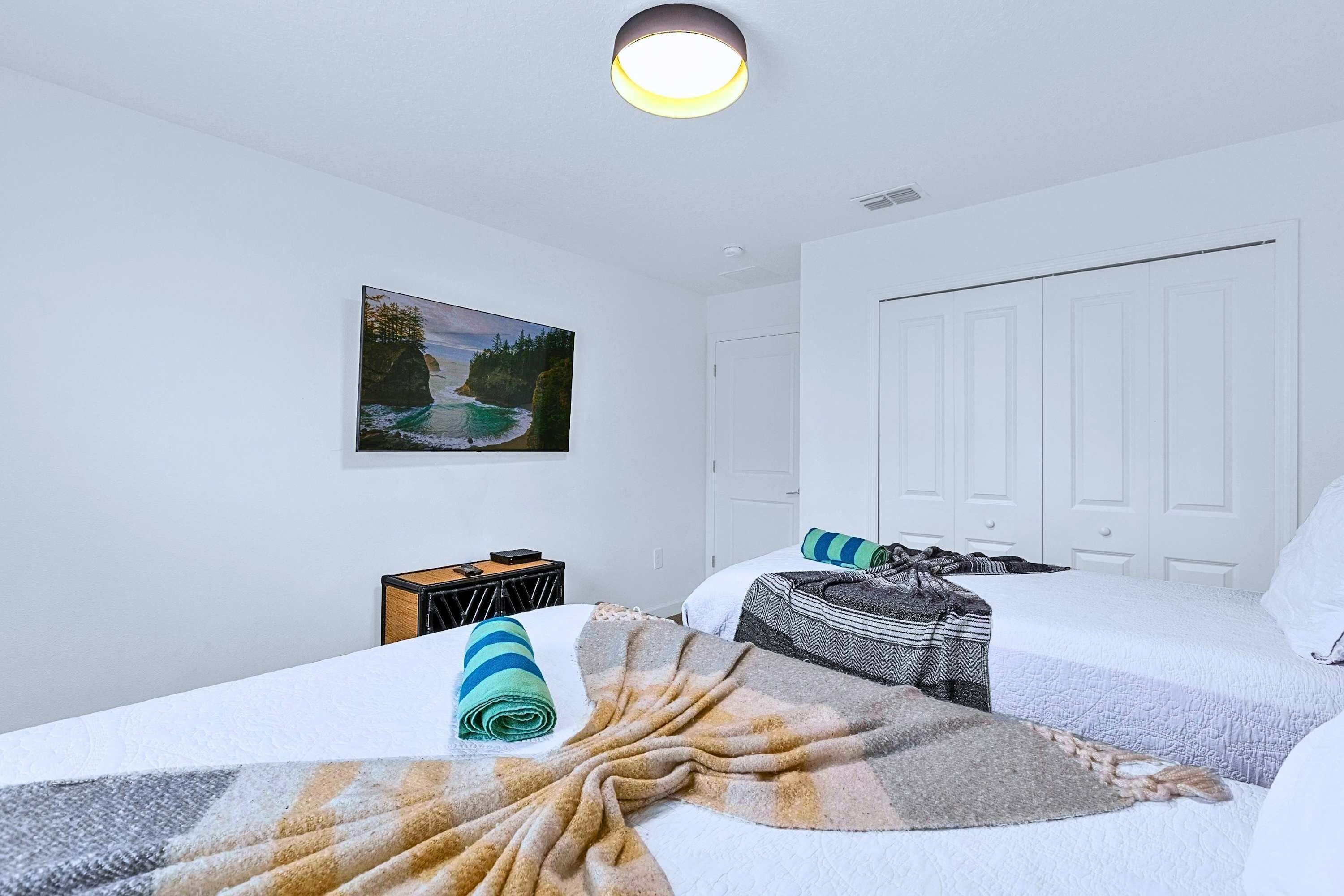 Une chambre avec deux lits, un tableau au mur, un bureau avec une chaise et une armoire.