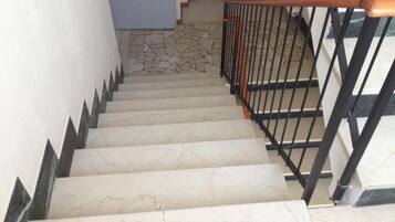 Un escalier avec des marches en marbre et une rampe en métal noir.