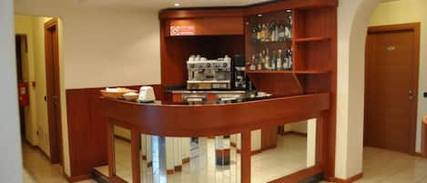 A hotel lobby with a curved reception desk, a coffee machine, and a liquor display.