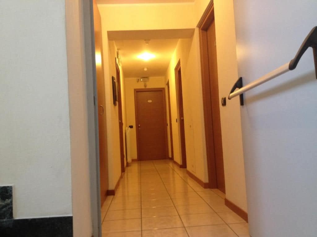 A hallway with a handrail, doors, and a light fixture on the ceiling.