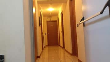 A hallway with a handrail, doors, and a light fixture on the ceiling.