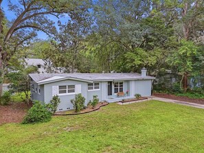 Ein eingeschossiges Haus mit einer Veranda, einem kleinen Garten und einem Weg zum Eingang.