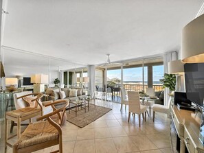 A spacious living area with a large TV, comfortable seating, and a view of the ocean. - Destin Pointe Magnolia House #306 | Luxe Condo, Beautiful Views + Amenities (Destin)