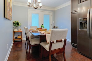 A dining area with a wooden table, chairs, and a refrigerator. - Indianapolis Escape, Easy Access to Dtwn! (Indianapolis)