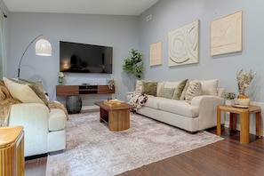 A modern living room with a flat-screen TV, a beige sofa, a coffee table, and a patterned rug. - Indianapolis Escape, Easy Access to Dtwn! (Indianapolis)