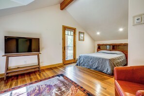 A bedroom with a bed, a television on a wooden stand, a door leading outside, and a red chair. - Retreat 7 Mi to Northstar Skiing! Easy I-80 Access (Truckee)