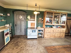 A kitchen with a vintage stove, wooden cabinets, and a hanging light fixture. - Ferienhaus Edeldorf by Interhome (Theisseil)