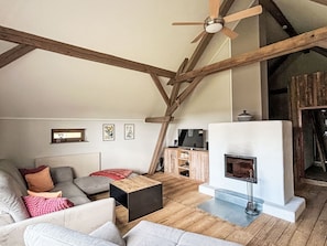 Un salón estilo loft con vigas de madera a la vista, una chimenea y un sofá moderno.