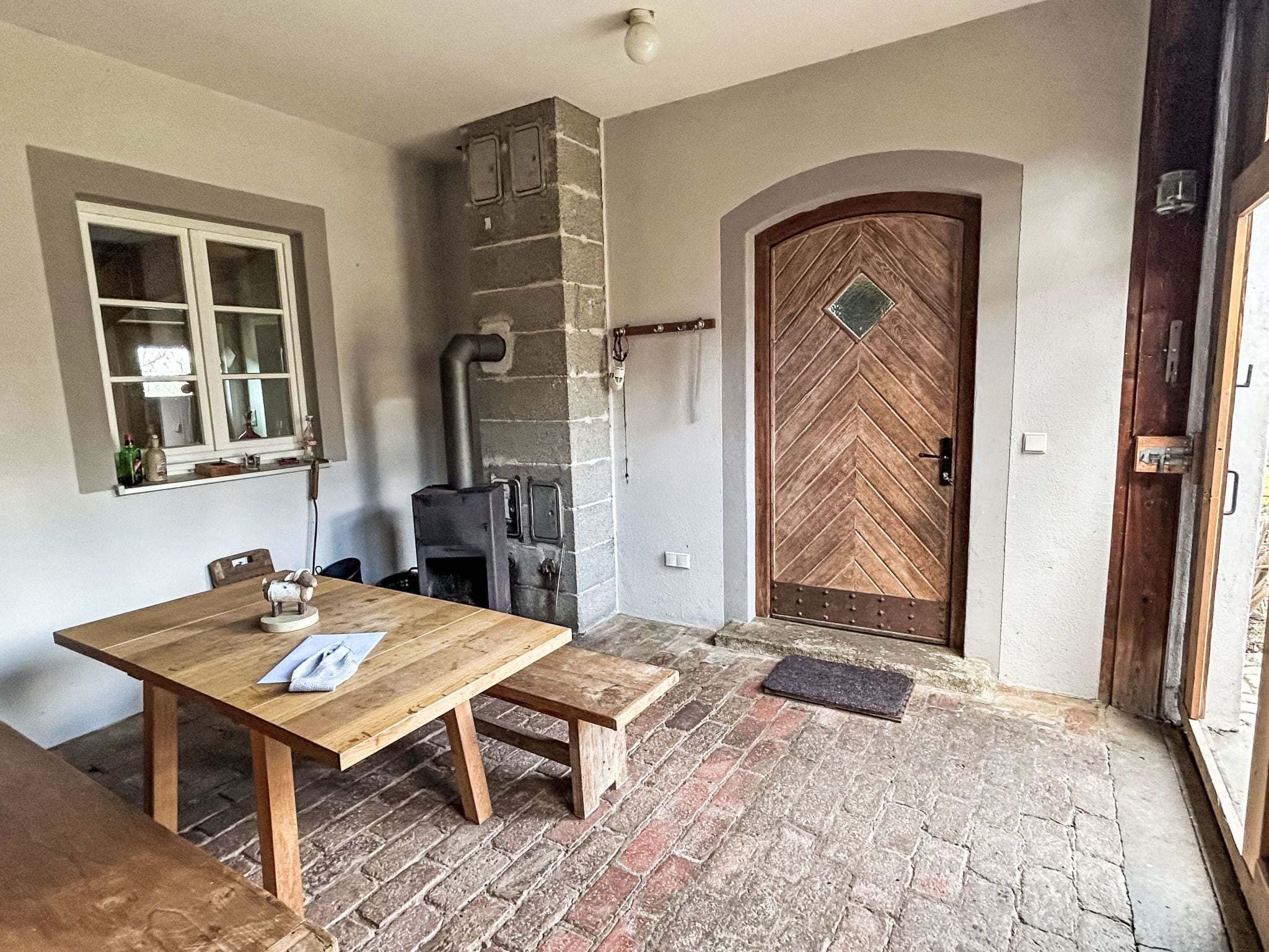A rustic interior with a wooden table, bench, and a stone fireplace.
