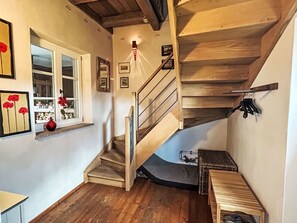 A wooden staircase leading to an upper floor, a window with a view, and a wall with framed pictures. - Ferienhaus Edeldorf by Interhome (Theisseil)