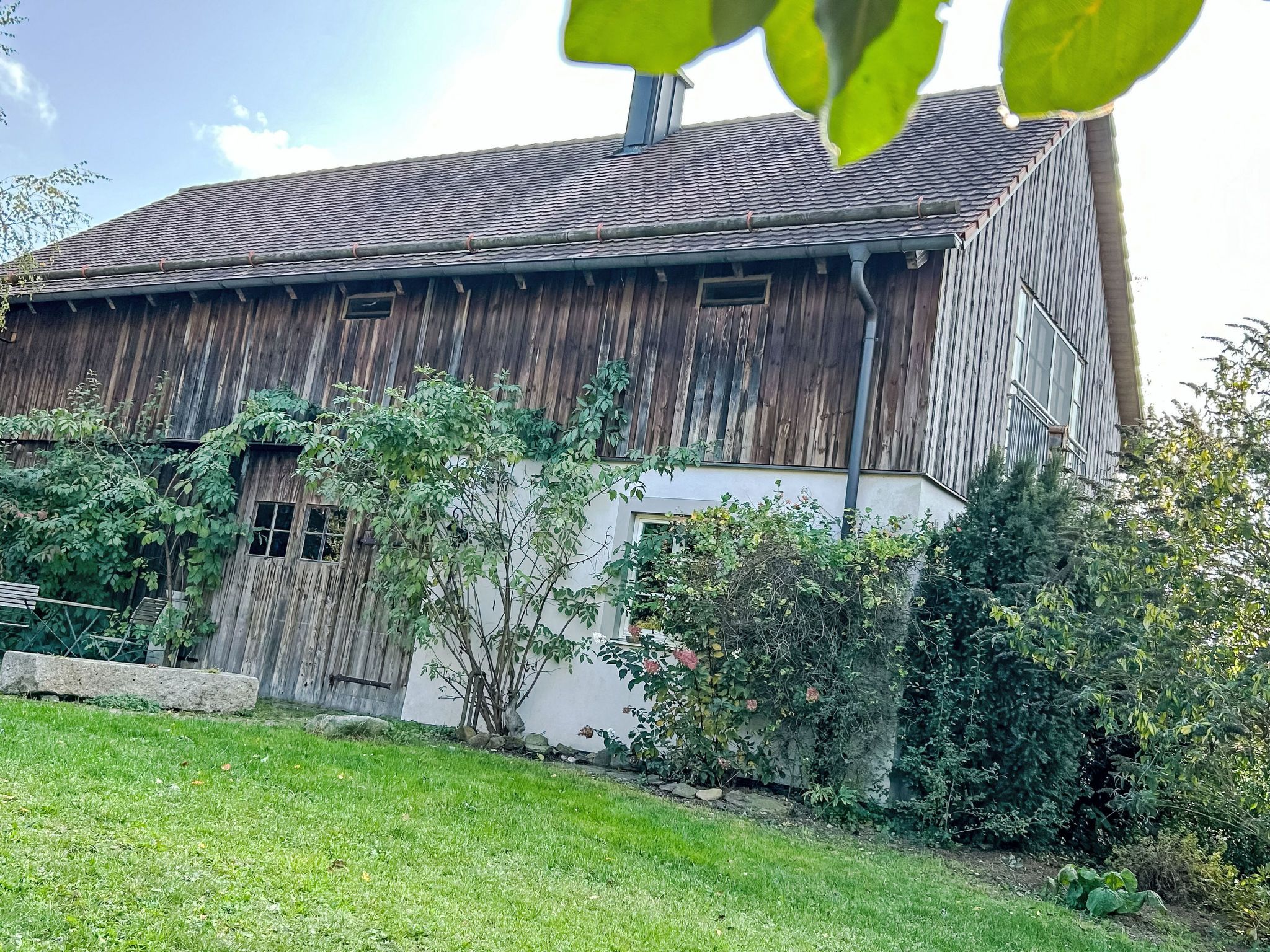 Une grange rustique avec un toit en pente, un revêtement en bois et une petite fenêtre.