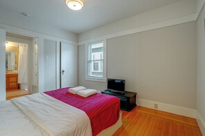 Ein Schlafzimmer mit Bett, Fernseher und Fenster mit Jalousien.