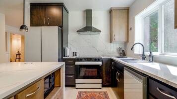 Una cocina moderna con una isla central, horno empotrado y un amplio ventanal que proporciona luz natural.