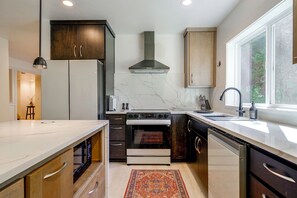 A modern kitchen with a central island, built-in oven, and a large window providing natural light. - Snohomish Executive Suite w/ Deck & Fire Pit (Snohomish)