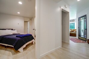 A bedroom with a bed, a door leading to another room, and a view of a balcony. - Snohomish Executive Suite w/ Deck & Fire Pit (Snohomish)