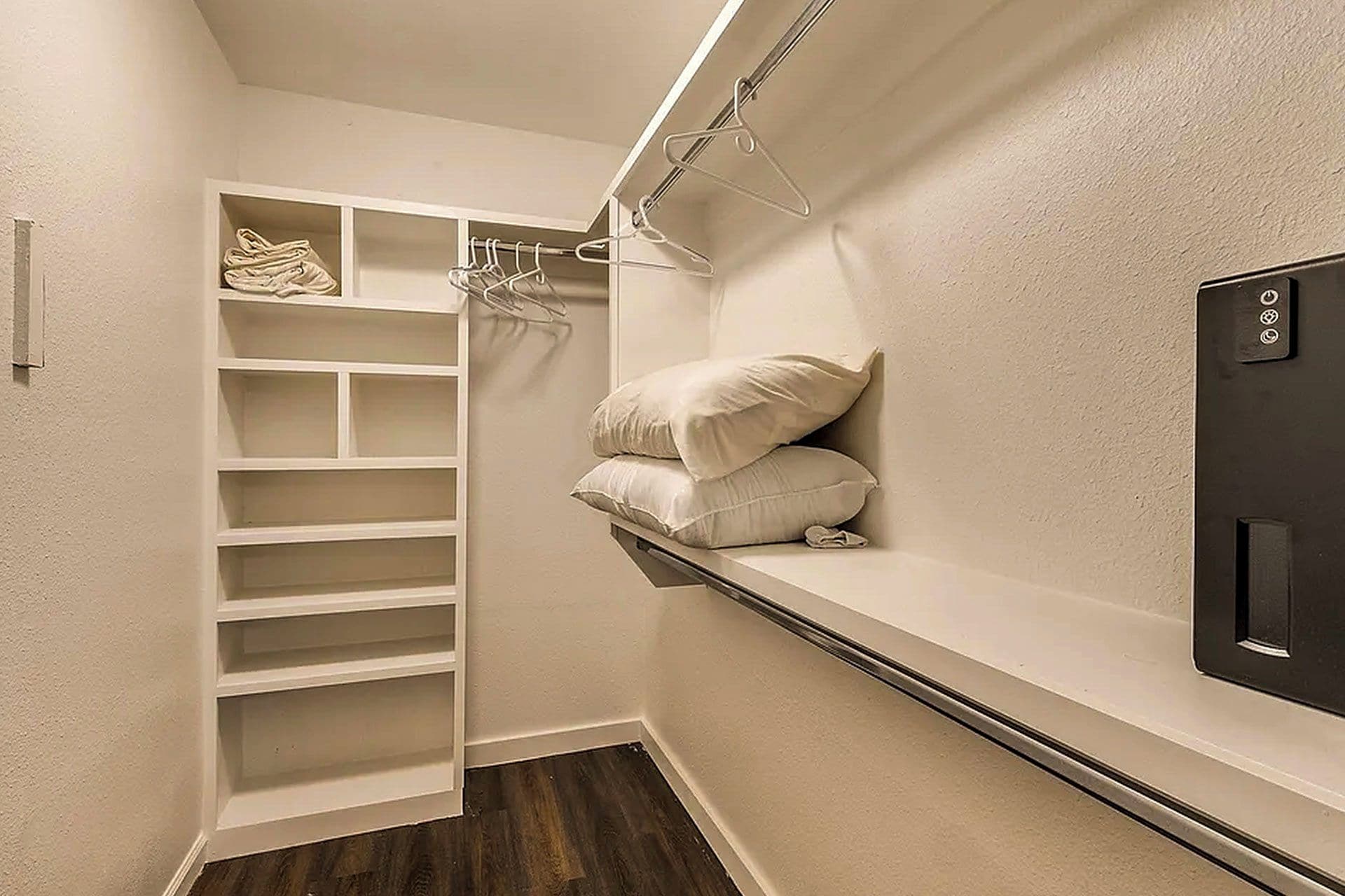 A walk-in closet with shelves, hanging space, and a built-in heater.