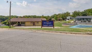 A community center with a sign, a covered outdoor area, and a pool.