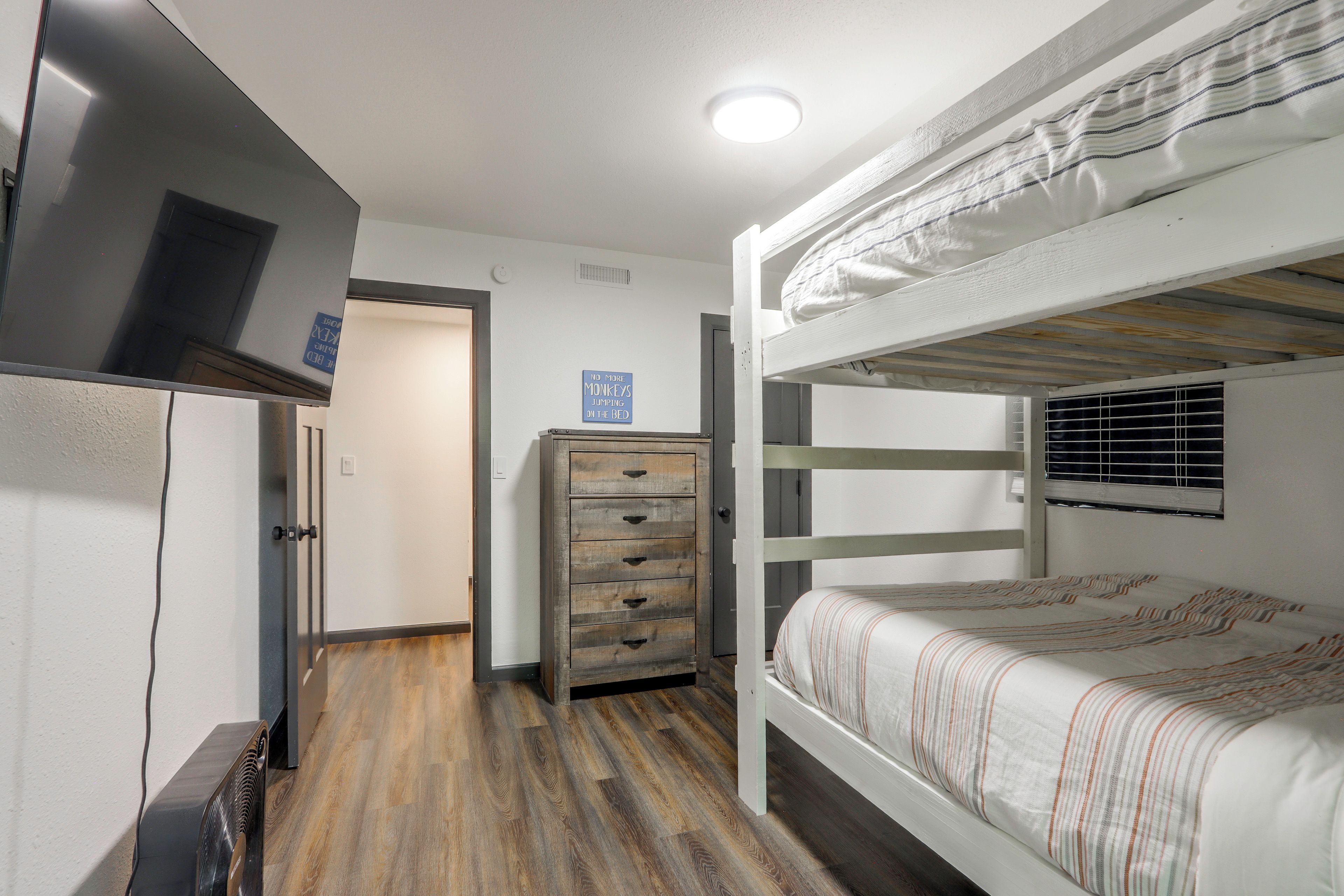 A bunk bed room with a dresser and a refrigerator.