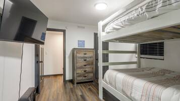 A bunk bed room with a dresser and a refrigerator.