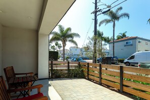 A balcony with a wooden fence, a chair, and a paved floor. - Walk to Beach! Condo w/ Shared Rooftop Patio (Oceanside)