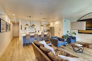 A modern kitchen with a central island, bar stools, and pendant lighting. - Walk to Beach! Condo w/ Shared Rooftop Patio (Oceanside)