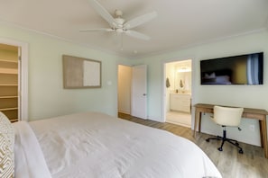 A bedroom with a bed, a desk, a chair, a ceiling fan, and a TV. - White Heron Landing - Waterfront New Bern Home! (New Bern)