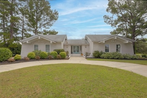 A two-story house with a front entrance, a driveway, and a well-maintained lawn.