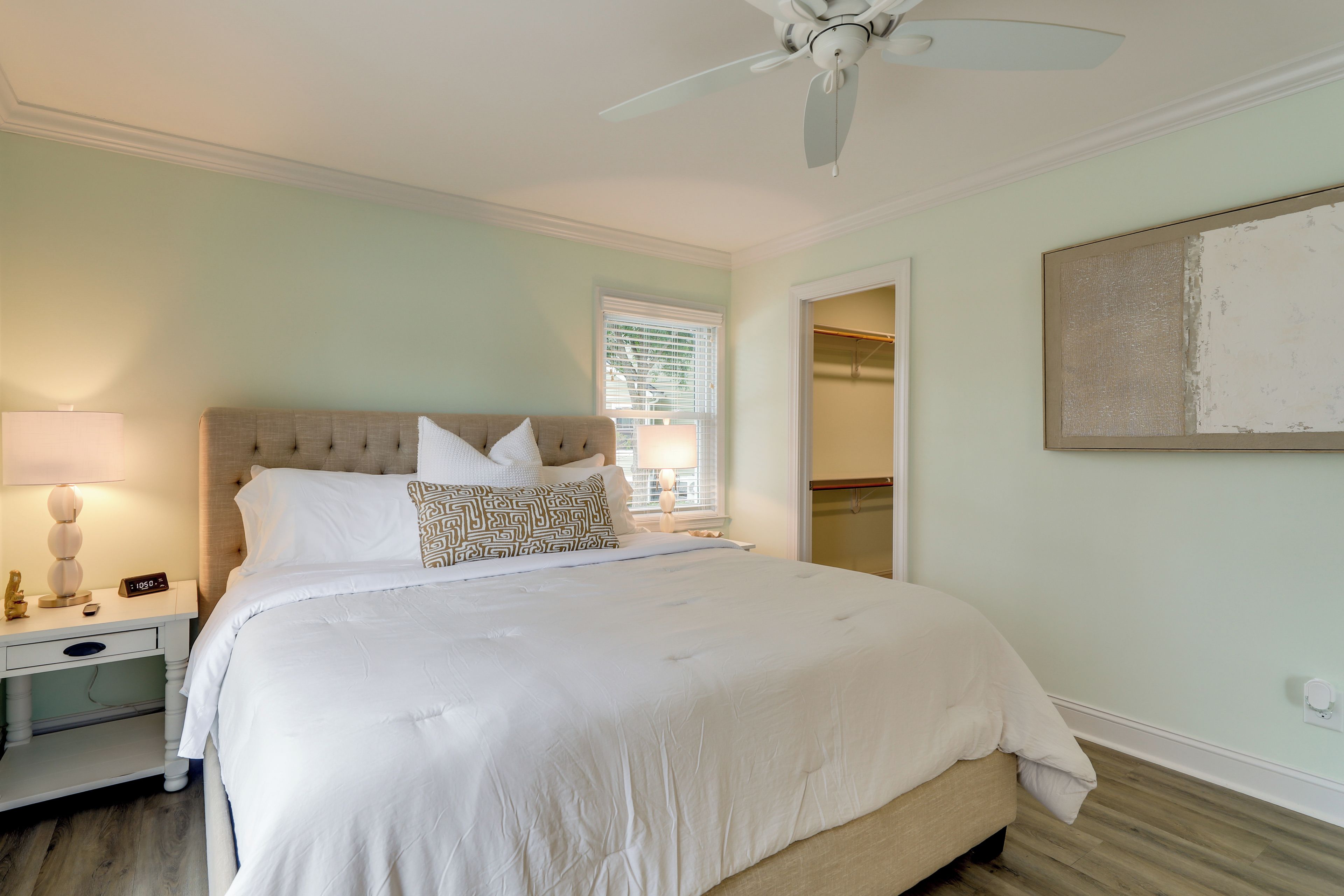A bedroom with a bed, nightstand, lamp, and a ceiling fan.