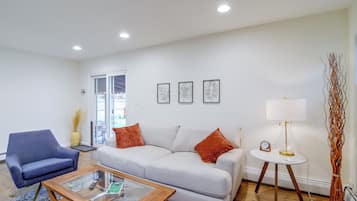 Una sala de estar con sofá, sillón, mesa de centro y lámpara.